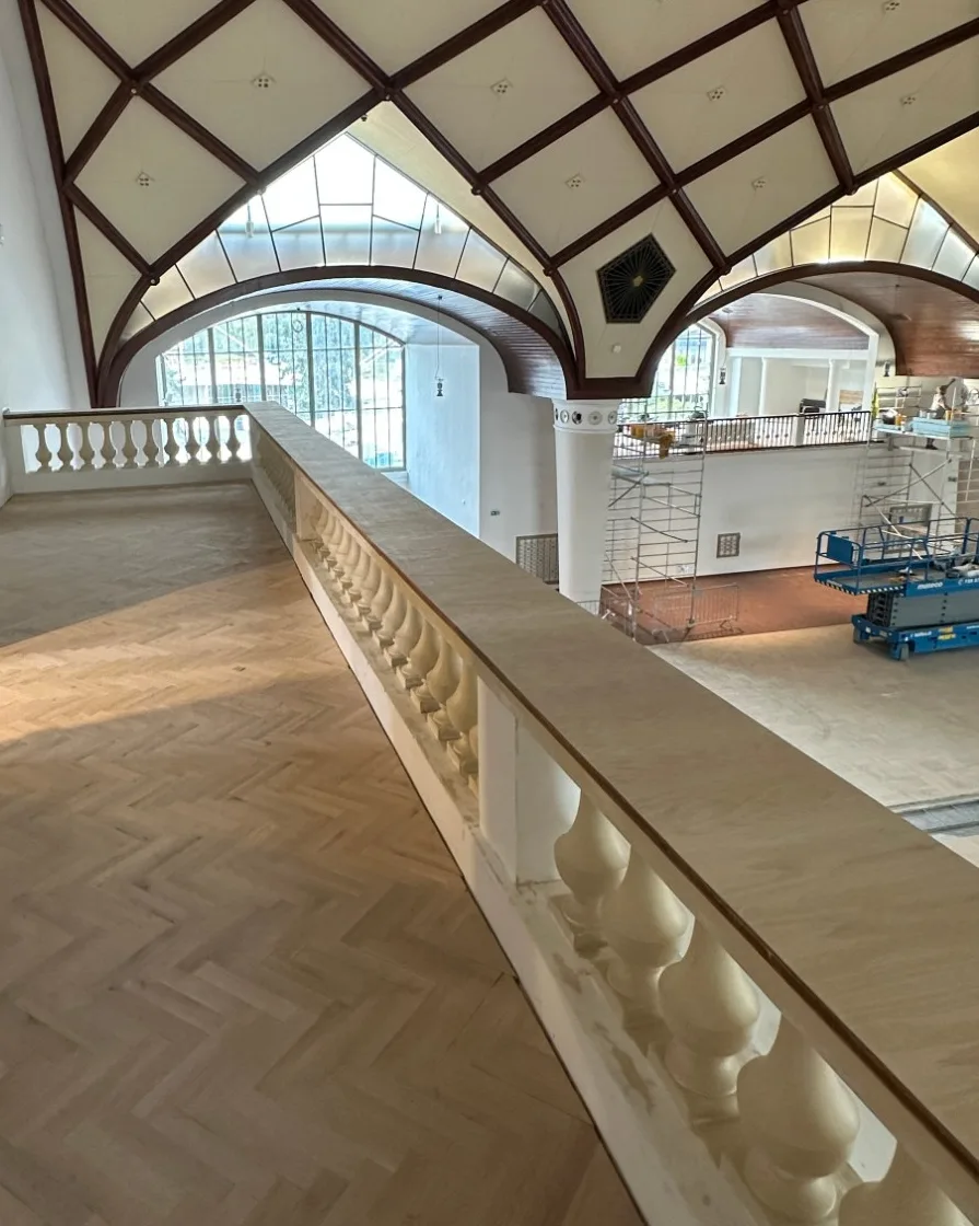 Dřevěné madlo na balustrádě galerie v historickém sále